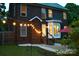 Exterior view of a brick home at dusk, featuring a patio with a red umbrella and string lights at 1120 Millwright Ln, Matthews, NC 28104