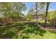 Expansive, partially shaded backyard with a mix of grass and mulch featuring a wood fence and mature trees at 1120 Millwright Ln, Matthews, NC 28104