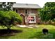 Lush backyard with a brick home, featuring a red umbrella and mature landscaping at 1120 Millwright Ln, Matthews, NC 28104