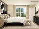 Sunlit bedroom with large window, neutral tones, and a cozy bench at the foot of the bed at 1188 Blackburn Cir, Edgemoor, SC 29712