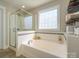 A relaxing bathroom featuring a soaking tub, a glass-enclosed shower, and a large window for natural light at 151 E Morehouse Ave, Mooresville, NC 28117