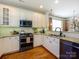 Modern kitchen with white cabinets, stainless steel appliances, and hardwood flooring at 151 E Morehouse Ave, Mooresville, NC 28117