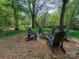 Cozy backyard fire pit area with Adirondack chairs surrounded by beautiful, mature trees at 4216 Maureen Dr, Charlotte, NC 28205