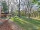 A beautifully landscaped backyard features mature trees, a stone pathway, and a cozy firepit area at 4216 Maureen Dr, Charlotte, NC 28205