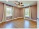 Spacious bedroom with hardwood floors, two windows with sheer curtains, and a ceiling fan at 4216 Maureen Dr, Charlotte, NC 28205