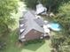 Aerial view displays the brick home with in-ground pool, brick patio, deck, and lush surrounding greenery at 4436 Roberta Rd, Concord, NC 28027