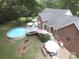 Aerial view showcasing backyard with above ground pool, brick patio, deck, and mature landscaping at 4436 Roberta Rd, Concord, NC 28027