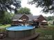 View of the brick home's expansive backyard featuring an above ground pool and an entertaining deck at 4436 Roberta Rd, Concord, NC 28027