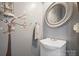 Powder room featuring a round mirror, decorative wall art, and a pedestal sink at 4436 Roberta Rd, Concord, NC 28027