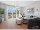 Bright living room with hardwood floors, modern decor, and a sliding glass door leading to a balcony at 5719 Castlerea Dr, Charlotte, NC 28217