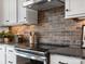 Close up of kitchen featuring stainless steel appliances, granite counters, and a beautiful brick backsplash at 5731 Castlerea Dr, Charlotte, NC 28217