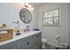 Stylish bathroom boasting a sleek vanity, round mirror, modern lighting, and neutral finishes at 5943 Charing Pl, Charlotte, NC 28211