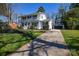 View of the white brick home with a double front porch and driveway leading to a two-car garage at 5943 Charing Pl, Charlotte, NC 28211