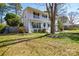 White brick home with a double front porch surrounded by a well-maintained lawn and mature trees at 5943 Charing Pl, Charlotte, NC 28211