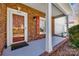 Cozy front porch with brick columns, shutters, and storm door at 7124 Bevington Woods Ln, Charlotte, NC 28277