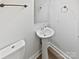 Cozy half-bathroom featuring a pedestal sink, modern fixtures, and a well-maintained toilet at 9832 Veronica Dr, Charlotte, NC 28215