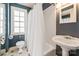 Well-lit bathroom features a white pedestal sink, toilet and tub with white tile and neutral paint at 103 S Laurel Ave, Charlotte, NC 28207