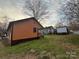 View of the backyard, showcasing the house exterior, lawn, and mature trees at 1128 Rosehill Dr, Lincolnton, NC 28092