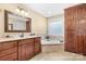 Bathroom featuring double vanity, soaking tub with tile surround, and a built-in linen closet at 1263 Waterford Dr, Hickory, NC 28602