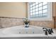 Close-up of bathtub with jets, tiled surround, and a decorative window at 1263 Waterford Dr, Hickory, NC 28602