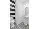 Stylish powder room with black and white striped accent wall, patterned floor tiles, and a pedestal sink at 14230 Morningate St, Huntersville, NC 28078