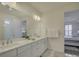 Bright bathroom featuring a double sink vanity with white cabinets, a large mirror, and access to the bedroom at 14230 Morningate St, Huntersville, NC 28078