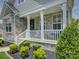 Inviting front porch with stone accents, white railings, and decorative landscaping at 14230 Morningate St, Huntersville, NC 28078