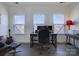 Bright home office featuring multiple windows, a modern desk setup, and comfortable seating at 14230 Morningate St, Huntersville, NC 28078