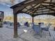 Beautiful covered patio area featuring an outdoor dining set, grill area and a stone fire pit with comfortable seating at 14230 Morningate St, Huntersville, NC 28078