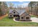 Eye-level view of a beautiful brick and stone home, enhanced by mature trees and an expansive manicured lawn at 1770 Cranwell Dr, Mt Ulla, NC 28125