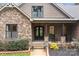Inviting front porch with rocking chairs, set against a backdrop of stone and brick architecture, accented with landscaping at 1770 Cranwell Dr, Mt Ulla, NC 28125