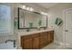 Bathroom featuring a dual sink vanity with granite countertops and a large mirror with elegant lighting at 17733 Colleton River Ln, Charlotte, NC 28278