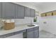 Well-organized laundry room with gray cabinetry, white marble countertops, and patterned tile flooring at 18512 Square Sail Rd, Cornelius, NC 28031