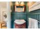 A jewel-toned bathroom with a wood vanity, framed mirror, sconce lighting, and wainscoting at 2144 Shadyview Dr, Charlotte, NC 28210