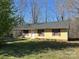 This home has a covered front door with a yellow exterior, black roof and red shutters at 2601 Bobwhite Cir, Wingate, NC 28174