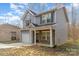 This two-story home has gray siding, a covered porch with stone accents, and an attached single-car garage at 3944 Wade E Morgan Rd, Charlotte, NC 28269