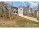 Two-story home features gray siding, front porch, two-car garage, and a long driveway nestled amongst the bare trees at 418 Wintergreen Ct, Kings Mountain, NC 28086
