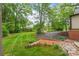 A backyard featuring a lush green lawn, a brick wall, and a stone patio with surrounding trees and landscaping at 600 S Central Ave, Belmont, NC 28012