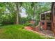 Brick home backyard featuring an enclosed patio, lush green grass, mature trees, and access to basement at 600 S Central Ave, Belmont, NC 28012