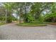 Gravel driveway leading to a charming home surrounded by mature trees and lush landscaping at 600 S Central Ave, Belmont, NC 28012