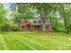 A well-maintained brick home with a manicured lawn, lush landscaping and large shade trees at 600 S Central Ave, Belmont, NC 28012