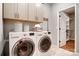 Well-lit laundry room featuring modern washer and dryer, gray cabinets, and a view into a storage closet at 1018 Heritage Pointe # 302, Indian Trail, NC 28079