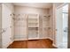 Spacious walk-in closet featuring custom shelving, hardwood floors, and access to the bathroom at 1018 Heritage Pointe # 302, Indian Trail, NC 28079