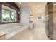 A bright bathroom features a soaking tub, vaulted ceilings, wood accents, and an exterior window at 19528 Mary Ardrey Cir, Cornelius, NC 28031