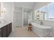 Bright bathroom featuring a soaking tub, glass shower, elegant fixtures, and a view from the window at 20637 Island Forest Dr, Cornelius, NC 28031