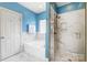 Modern blue bathroom with a large tub, glass shower, and tiled walls at 4633 River Bluff Ct, Charlotte, NC 28214