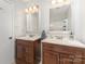 Bathroom featuring dual sinks with dark wood cabinets, and bright vanity lighting at 7212 Hackberry Ln, Charlotte, NC 28226