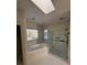 Bright bathroom with skylight, tiled floor, and glass-enclosed shower at 8011 Greencastle Dr, Charlotte, NC 28210