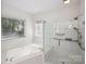 Bright bathroom with glass enclosed shower and soaking tub with tiled surround at 8011 Greencastle Dr, Charlotte, NC 28210