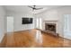 Spacious living room featuring hardwood floors, fireplace, and a ceiling fan for comfortable living at 8011 Greencastle Dr, Charlotte, NC 28210